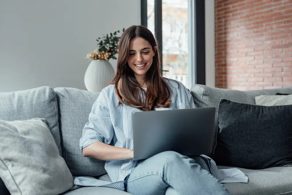 Young woman working on a laptop in a cozy living room, representing modern marketing practices with Lyfe AI.